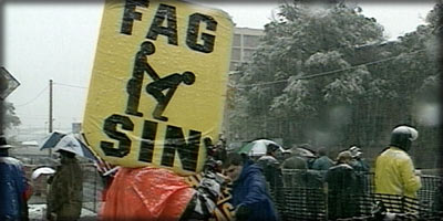 photo of person holding a sign that says 'fag sin'