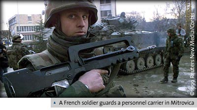 A French soldier guards a personnel carrier in Mitrovica