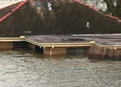 Photo of a house with flood waters approaching the roof.