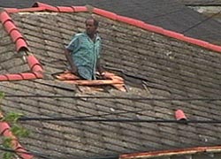 New Orleans resident climbing through roof of house.